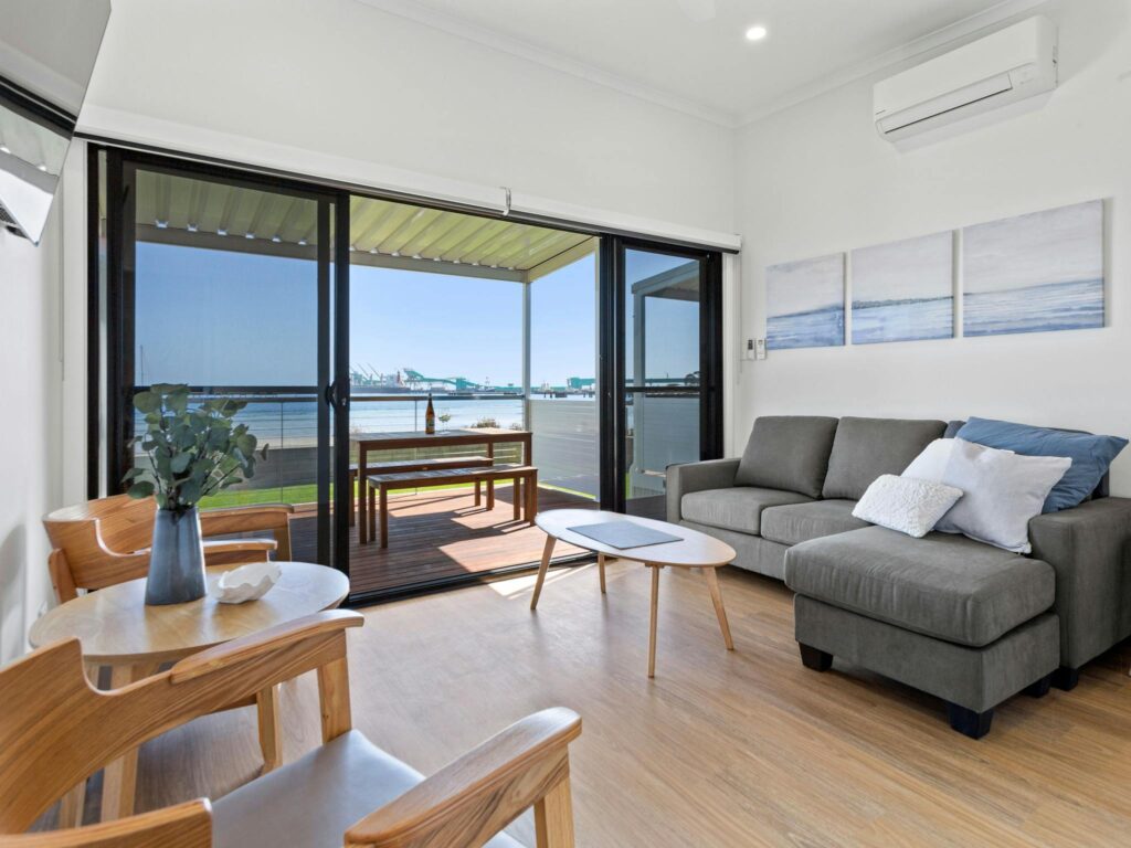 Interior lounge/dining area of Apartment 5, including lounge with chaise, artwork and view to beach.