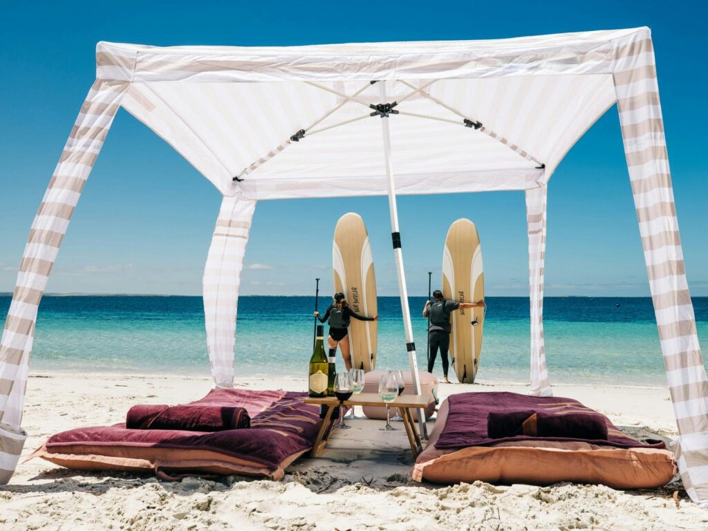 Two people with paddleboards standing in front of beach cabana, Louth Island