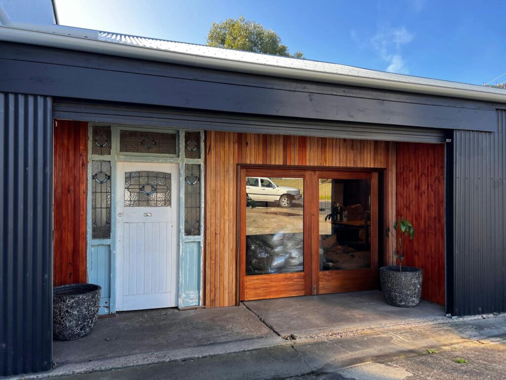 Eyre roasted garage with vintage door, wooden accents, plants, and a parked car outside