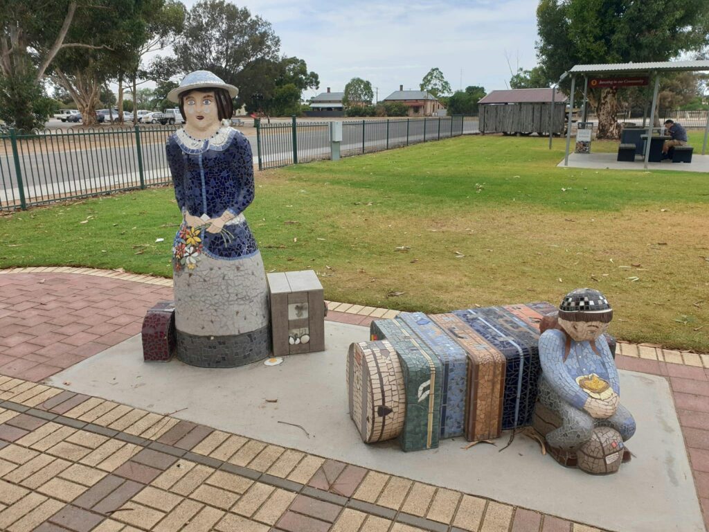 This artwork depicts an iconic pioneer woman Dulcie, waiting with luggage to board a train